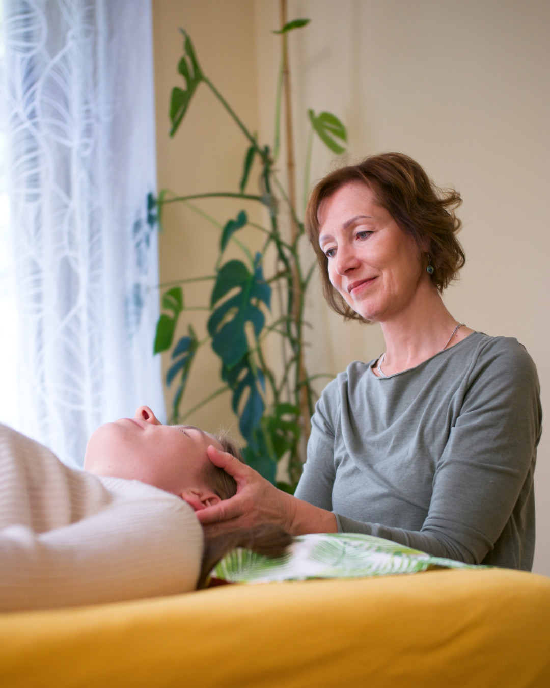 Mag. Silvia Pruckner bei einer craniosacralen Behandlung am Kopf einer Klientin in ihrer Praxis in Wien